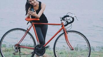 Happy young Asian woman while riding a bicycle in a city park. She smiled using the bicycle of transportation. Environmentally friendly concept. video