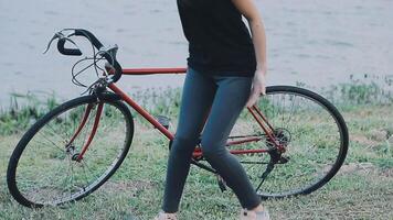 contento joven asiático mujer mientras montando un bicicleta en un ciudad parque. ella sonrió utilizando el bicicleta de transporte. ambientalmente simpático concepto. video