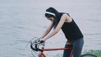 contento giovane asiatico donna mentre equitazione un' bicicletta nel un' città parco. lei sorrise utilizzando il bicicletta di trasporto. l'ambiente amichevole concetto. video