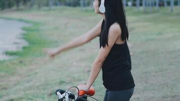 Happy young Asian woman while riding a bicycle in a city park. She smiled using the bicycle of transportation. Environmentally friendly concept. video