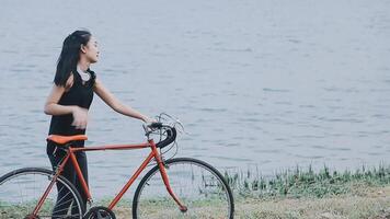 contento giovane asiatico donna mentre equitazione un' bicicletta nel un' città parco. lei sorrise utilizzando il bicicletta di trasporto. l'ambiente amichevole concetto. video