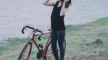 contento joven asiático mujer mientras montando un bicicleta en un ciudad parque. ella sonrió utilizando el bicicleta de transporte. ambientalmente simpático concepto. video