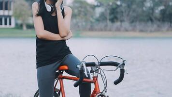 Happy young Asian woman while riding a bicycle in a city park. She smiled using the bicycle of transportation. Environmentally friendly concept. video