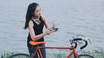 Happy young Asian woman while riding a bicycle in a city park. She smiled using the bicycle of transportation. Environmentally friendly concept. video