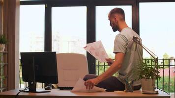 Manager or CEO of start up company looking at graphs on paper while warm sunset light is hitting from behind in big windows. Portrait of successful entrepreneur video