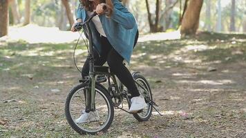 contento asiático hermosa joven mujer montando bicicleta en calle al aire libre cerca edificio ciudad, retrato de sonriente hembra estilo de vida utilizando bicicleta en verano viaje medio de transporte, eco simpático video