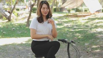 contento asiático hermosa joven mujer montando bicicleta en calle al aire libre cerca edificio ciudad, retrato de sonriente hembra estilo de vida utilizando bicicleta en verano viaje medio de transporte, eco simpático video