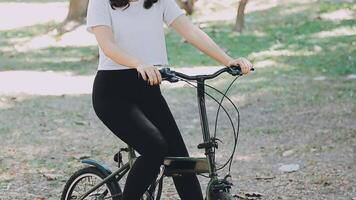 feliz ásia lindo jovem mulher equitação bicicleta em rua ao ar livre perto construção cidade, retrato do sorridente fêmea estilo de vida usando bicicleta dentro verão viagem significa do transporte, eco amigáveis video