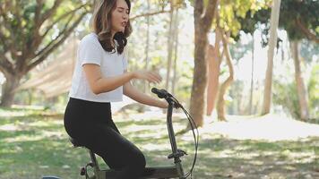 contento asiatico bellissimo giovane donna equitazione bicicletta su strada all'aperto vicino edificio città, ritratto di sorridente femmina stile di vita utilizzando bicicletta nel estate viaggio si intende di trasporto, eco amichevole video