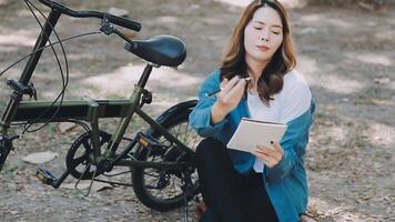 content asiatique magnifique Jeune femme équitation vélo sur rue Extérieur près bâtiment ville, portrait de souriant femelle mode de vie en utilisant bicyclette dans été Voyage veux dire de transport, éco amical video