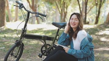 Lycklig asiatisk skön ung kvinna ridning cykel på gata utomhus- nära byggnad stad, porträtt av leende kvinna livsstil använder sig av cykel i sommar resa betyder av transport, eco vänlig video