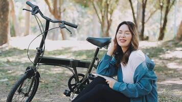 contento asiático hermosa joven mujer montando bicicleta en calle al aire libre cerca edificio ciudad, retrato de sonriente hembra estilo de vida utilizando bicicleta en verano viaje medio de transporte, eco simpático video