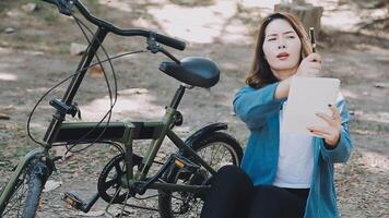 content asiatique magnifique Jeune femme équitation vélo sur rue Extérieur près bâtiment ville, portrait de souriant femelle mode de vie en utilisant bicyclette dans été Voyage veux dire de transport, éco amical video