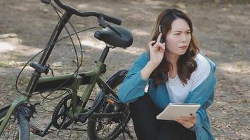 contento asiatico bellissimo giovane donna equitazione bicicletta su strada all'aperto vicino edificio città, ritratto di sorridente femmina stile di vita utilizzando bicicletta nel estate viaggio si intende di trasporto, eco amichevole video