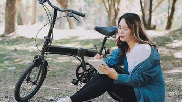 Happy Asian beautiful young woman riding bicycle on street outdoor near building city, Portrait of smiling female lifestyle using bike in summer travel means of transportation, ECO friendly video