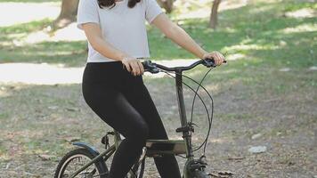 contento asiático hermosa joven mujer montando bicicleta en calle al aire libre cerca edificio ciudad, retrato de sonriente hembra estilo de vida utilizando bicicleta en verano viaje medio de transporte, eco simpático video