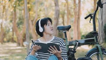 gesund und aktiv Lebensstil, gehen zu Arbeit auf Öko Transport. lächelnd attraktiv tausendjährig männlich Mitarbeiter im Brille mit Tasche und Tasse von wegbringen Kaffee, ziehen um Fahrrad im Stadt Park im Sommer, draussen video