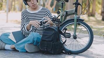 gesund und aktiv Lebensstil, gehen zu Arbeit auf Öko Transport. lächelnd attraktiv tausendjährig männlich Mitarbeiter im Brille mit Tasche und Tasse von wegbringen Kaffee, ziehen um Fahrrad im Stadt Park im Sommer, draussen video