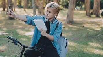 retrato do uma feliz jovem homem vestido dentro camisa com saco equitação em uma bicicleta ao ar livre video