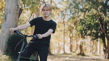 retrato de un contento joven hombre vestido en camisa con bolso montando en un bicicleta al aire libre video