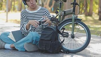 gesund und aktiv Lebensstil, gehen zu Arbeit auf Öko Transport. lächelnd attraktiv tausendjährig männlich Mitarbeiter im Brille mit Tasche und Tasse von wegbringen Kaffee, ziehen um Fahrrad im Stadt Park im Sommer, draussen video