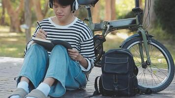 gezond en actief levensstijl, gaan naar werk Aan eco vervoer. glimlachen aantrekkelijk millennial mannetje werknemer in bril met zak en kop van meenemen koffie, in beweging fiets in stad park in zomer, buitenshuis video