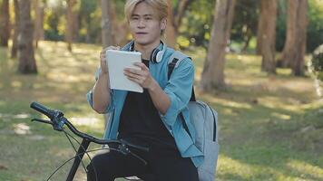 Portrait of a happy young man dressed in shirt with bag riding on a bicycle outdoors video