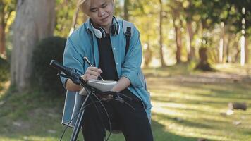 retrato do uma feliz jovem homem vestido dentro camisa com saco equitação em uma bicicleta ao ar livre video