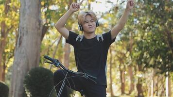 porträtt av en Lycklig ung man klädd i skjorta med väska ridning på en cykel utomhus video