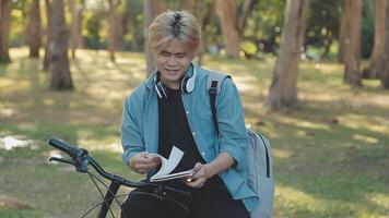 Portrait of a happy young man dressed in shirt with bag riding on a bicycle outdoors video