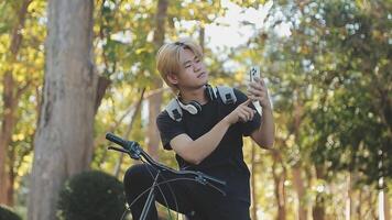 retrato de un contento joven hombre vestido en camisa con bolso montando en un bicicleta al aire libre video