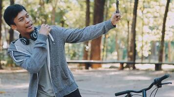 en stilig ung man går till de stad med hans cykel. han är Sammanträde på en cykel och sändning text meddelande på de smartphone. video