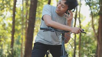 A handsome young man goes to the city with his bike. He is sitting on a bike and sending text message on the smartphone. video