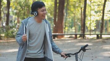 un' bello giovane uomo va per il città con il suo bicicletta. lui è seduta su un' bicicletta e invio testo Messaggio su il smartphone. video