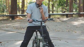 A handsome young man goes to the city with his bike. He is sitting on a bike and sending text message on the smartphone. video