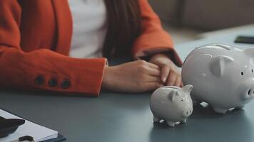 Female hand putting coin into piggy bank closeup video