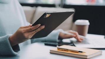 Woman hand holding white mobile phone on a table with a laptop in office. video