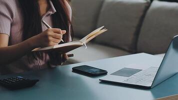 Woman hand holding white mobile phone on a table with a laptop in office. video