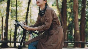 bicicleta, mujer y teléfono en ciudad sensación emocionado y contento acerca de mensaje mientras al aire libre en verano con de moda mirar. eco simpático transporte para carbón huella hembra en un bicicleta utilizando 5g red video