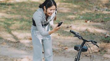 content fille en train de regarder médias dans une intelligent téléphone séance dans le rue à côté de sa vélo video