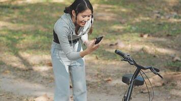 content fille en train de regarder médias dans une intelligent téléphone séance dans le rue à côté de sa vélo video