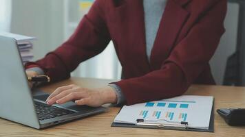 Asian Businesswoman Using laptop computer and working at office with calculator document on desk, doing planning analyzing the financial report, business plan investment, finance analysis concept. video