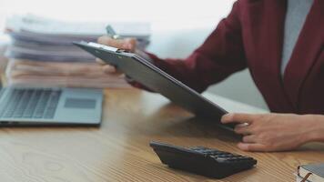 Asian Businesswoman Using laptop computer and working at office with calculator document on desk, doing planning analyzing the financial report, business plan investment, finance analysis concept. video