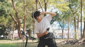 asiático hombre viajero utilizando inteligente teléfono mientras sentado en el ciudad parque en hermosa día. viajar, vacaciones y viaje concepto video