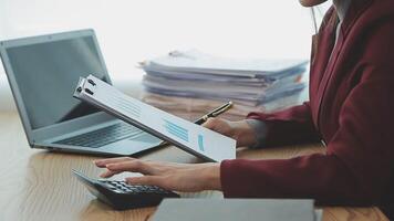 Asian Businesswoman Using laptop computer and working at office with calculator document on desk, doing planning analyzing the financial report, business plan investment, finance analysis concept. video