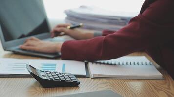 Asian Businesswoman Using laptop computer and working at office with calculator document on desk, doing planning analyzing the financial report, business plan investment, finance analysis concept. video