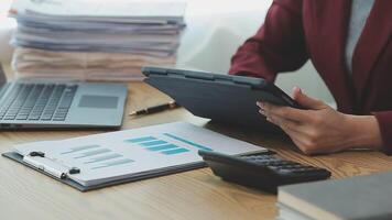 Asian Businesswoman Using laptop computer and working at office with calculator document on desk, doing planning analyzing the financial report, business plan investment, finance analysis concept. video