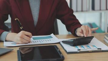 Asian Businesswoman Using laptop computer and working at office with calculator document on desk, doing planning analyzing the financial report, business plan investment, finance analysis concept. video