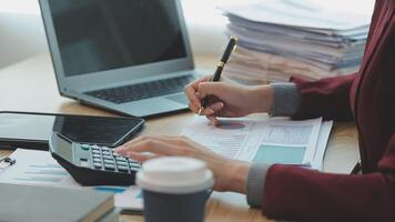 Asian Businesswoman Using laptop computer and working at office with calculator document on desk, doing planning analyzing the financial report, business plan investment, finance analysis concept. video