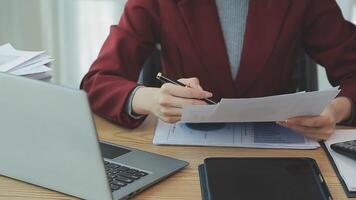Asian Businesswoman Using laptop computer and working at office with calculator document on desk, doing planning analyzing the financial report, business plan investment, finance analysis concept. video